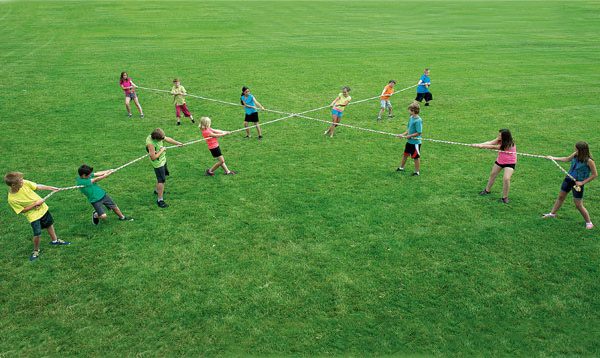 13 People Playing 4 Way Tug Of War on Grass Field