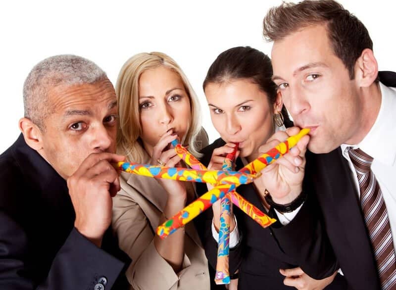 4 People In Suits Blowing Into Party Blowers