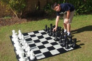 Boy Playing With Giant Chess Set in Garden