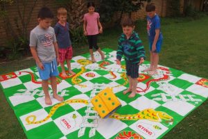 Children Playing Giant Snakes and Ladders in Garden